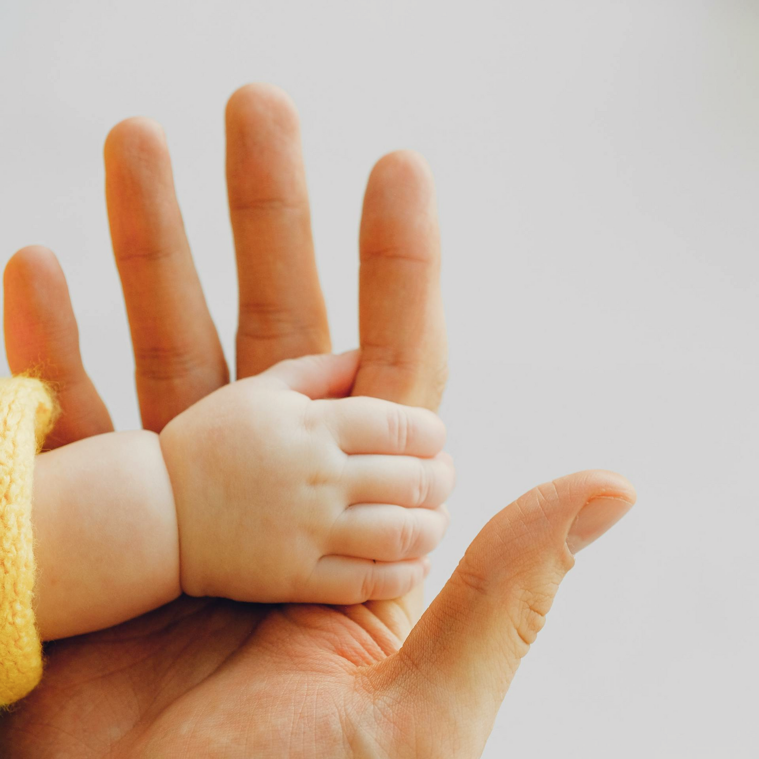Baby's hand gently touching a mom's hand to represent The Daisy Refillery's sensitive skin collection, which is perfect for babies and those with sensitive skin.
